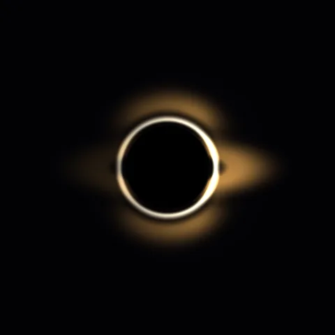 A dark circular core is surrounded by a warm, distorted ring of light.